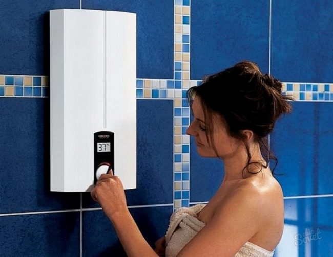 une fille se tient près d'un chauffe-eau électrique