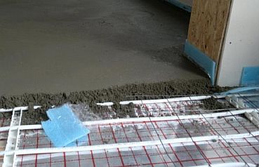 Photo - Coulage de la chape de béton sur la conduite de chauffage par le sol
