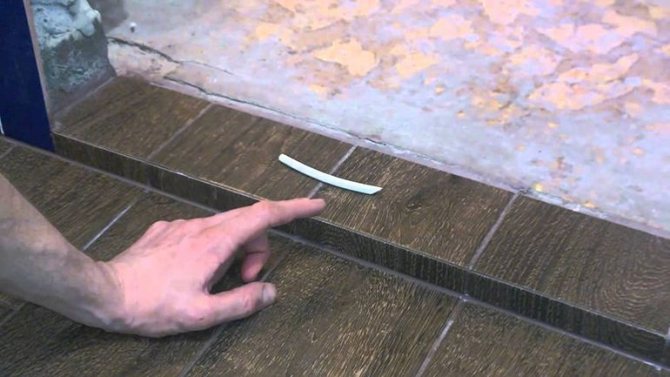 Installation d'un seuil en plastique d'une porte de balcon sur une chape