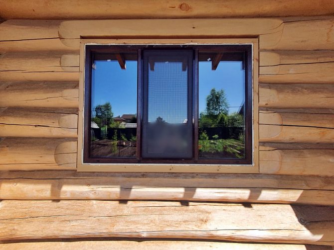 Ouverture de la fenêtre dans une maison en rondins sous une fenêtre en plastique - vue extérieure