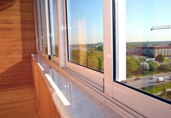 Fenêtres coulissantes en plastique sur un balcon meublé