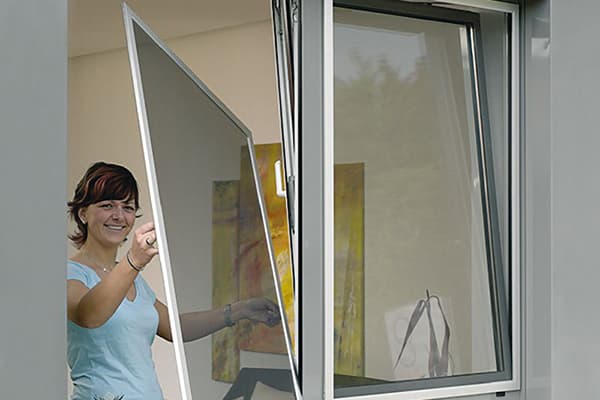 La femme enlève le filet de la fenêtre